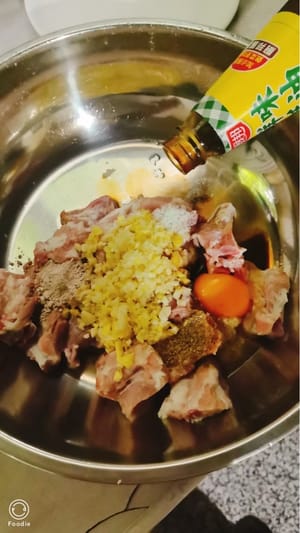 Anche questo passaggio è molto importante. Aggiungete i condimenti sopra indicati, mezzo cucchiaio d'olio, mezzo cucchiaio di salsa di ostriche, mezzo cucchiaio di salsa di soia, la giusta quantità di sale, un cucchiaio di amido di mais, un terzo di cucchiaio di pepe, l'aglio e lo zenzero tritati e un uovo. Questo passaggio è molto critico. Continuate a mescolare uniformemente per mantenere l'umidità in modo che le costine siano tenere e non secche dopo la cottura a vapore.