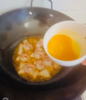 Vierta los huevos sazonados uniformemente en la olla y cocine durante 1 minuto. Vierta la salsa uniformemente sobre los huevos. Espolvoree con chile picante y apague el fuego.