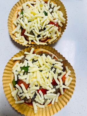 Pizza Sosis dan Udang Cara Merakit: Oleskan saus pizza tebal-tebal pada alas pizza mini, beri topping sosis, udang, dan paprika hijau dan merah, lalu tutupi dengan tumpukan keju mozzarella yang tebal. Toppingnya sangat melimpah hingga hampir tumpah!