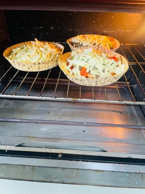 Pizza Lezat Panggang Oven: Letakkan kedua pizza di rak tengah oven dan panggang pada suhu 180°C selama kurang lebih 12 menit, atau hingga keju meleleh dan kenyal. Selesai!