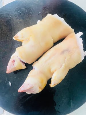 Zuerst die Haare von den Schweinsfüßen abflämmen und diese sauber schaben. Anschließend in einen Topf mit kaltem Wasser, Ingwerscheiben, Kochwein und Sichuanpfeffer geben. Sobald das Wasser kocht, 5 Minuten kochen lassen, dann herausnehmen und gründlich abspülen.