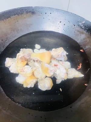 In einem separaten Topf ausreichend Wasser, einen Löffel Salz, geschnittenen Ingwer und zwei Esslöffel Kochwein geben. Die Schweinsfüße hinzufügen und nach dem Aufkochen des Wassers 35 Minuten bei schwacher Hitze köcheln lassen.