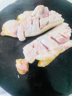 Zuerst die Haare von den Schweinsfüßen abflämmen und diese sauber schaben. Anschließend in einen Topf mit kaltem Wasser, Ingwerscheiben, Kochwein und Sichuanpfeffer geben. Sobald das Wasser kocht, 5 Minuten kochen lassen, dann herausnehmen und gründlich abspülen.