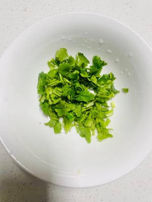 Koriander waschen und hacken, 3 Esslöffel helle Sojasauce hinzufügen und gut vermischen.