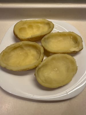 Évidez les pommes de terre jusqu’à obtenir une forme de bol. Écrasez la chair pour la farce au bœuf.