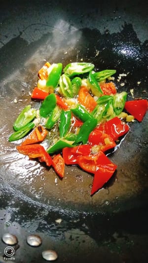 锅中留油倒入蒜片，青红辣椒翻炒均匀。