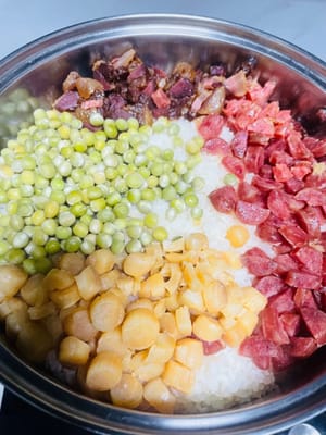 Den Klebreis abspülen und in einen Dampfgarer geben. Anschließend die gehackte Wurst, den Pökelfleisch und die getrockneten Jakobsmuscheln darauf verteilen. Ich habe eingeweichte, getrocknete grüne Bohnen verwendet, die daher länger dämpfen müssen. Falls Sie frische grüne Bohnen verwenden, geben Sie diese 5 Minuten vor Ende der Garzeit des Klebreis hinzu. Sobald das Wasser kocht, den Reis bei mittlerer bis niedriger Hitze 30–35 Minuten dämpfen.