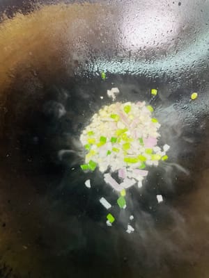 Öl in einer Pfanne bei niedriger Hitze erhitzen. Zwiebeln und die weißen Teile der Frühlingszwiebeln hinzufügen und anbraten, bis sie duften. Dann die getrockneten Garnelen dazugeben und kurz anbraten, bis sie duften. Anschließend das gepökelte Schweinefleisch und die Wurst dazugeben und anbraten, bis das Fett ausgelassen ist. Nicht zu stark erhitzen, da das Fleisch sonst trocken und zäh wird. Zum Schluss die Shiitake-Pilze dazugeben und einige Minuten mitbraten.