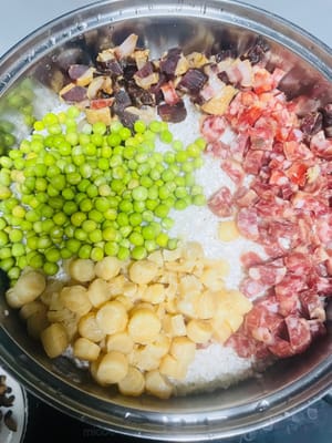 Den Klebreis abspülen und in einen Dampfgarer geben. Anschließend die gehackte Wurst, den Pökelfleisch und die getrockneten Jakobsmuscheln darauf verteilen. Ich habe eingeweichte, getrocknete grüne Bohnen verwendet, die daher länger dämpfen müssen. Falls Sie frische grüne Bohnen verwenden, geben Sie diese 5 Minuten vor Ende der Garzeit des Klebreis hinzu. Sobald das Wasser kocht, den Reis bei mittlerer bis niedriger Hitze 30–35 Minuten dämpfen.