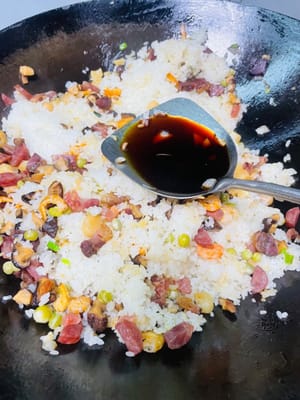 Den gedämpften Klebreis und die restlichen Zutaten in einen Topf geben, kurz anbraten und dann 1 Esslöffel helle Sojasauce, 1 Teelöffel Salz und 1 Esslöffel Austernsauce zum Würzen hinzufügen. Zum Schluss mit gerösteten Erdnüssen und gehackten Frühlingszwiebeln bestreuen, gut vermischen und genießen!