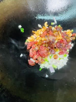 Öl in einer Pfanne bei niedriger Hitze erhitzen. Zwiebeln und die weißen Teile der Frühlingszwiebeln hinzufügen und anbraten, bis sie duften. Dann die getrockneten Garnelen dazugeben und kurz anbraten, bis sie duften. Anschließend das gepökelte Schweinefleisch und die Wurst dazugeben und anbraten, bis das Fett ausgelassen ist. Nicht zu stark erhitzen, da das Fleisch sonst trocken und zäh wird. Zum Schluss die Shiitake-Pilze dazugeben und einige Minuten mitbraten.