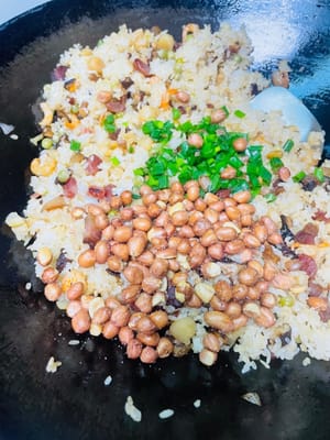 Den gedämpften Klebreis und die restlichen Zutaten in einen Topf geben, kurz anbraten und dann 1 Esslöffel helle Sojasauce, 1 Teelöffel Salz und 1 Esslöffel Austernsauce zum Würzen hinzufügen. Zum Schluss mit gerösteten Erdnüssen und gehackten Frühlingszwiebeln bestreuen, gut vermischen und genießen!