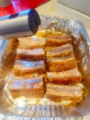 Once the pork is done marinating, transfer onto an aluminium baking tray and spray with oil on both sides