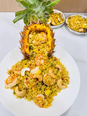 Für einen süß-sauren Geschmack einen Esslöffel Ananassaft hinzufügen, dann die gewürfelte Ananas dazugeben und weiterbraten. Falls Currypulver verwendet wird, dieses jetzt dazugeben und gut verrühren. Abschmecken und abschmecken. Wenn das Curry insgesamt salzig genug ist, einen Esslöffel Salz zum Currypulver geben. Zum Schluss auf einem Teller servieren, mit gekochten Cashewnüssen bestreuen und für eine interessantere Präsentation Ananasschalen verwenden.