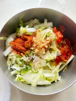 Put chili powder, garlic, sour tomato sauce, salt, and soy sauce on the three-color vegetable and mix them with gloves for 2 minutes. Hygiene is important.