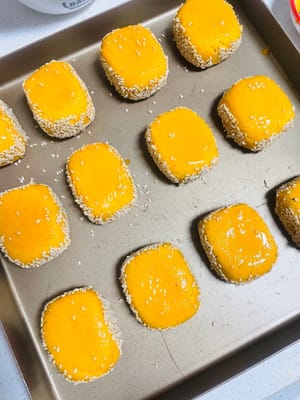 成形したサツマイモの端を水で湿らせ、白ゴマに転がしてしっかりとくっつけます。