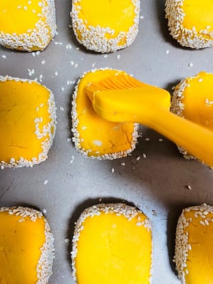 成形したサツマイモの端を水で湿らせ、白ゴマに転がしてしっかりとくっつけます。