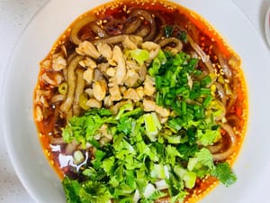 Versare i noodles di riso cotti in una ciotola, guarnire con ravanelli secchi saltati in padella e fagioli dall'occhio sottaceto, cospargere con coriandolo e cipollotti tritati e aggiungere qualche arachidi.