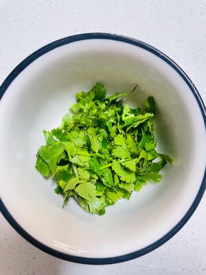 Lavare e tritare il coriandolo e i cipollotti.