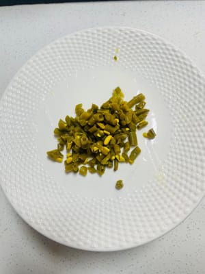 Preparare i contorni: tagliare a pezzetti i fagiolini sottaceto e il ravanello secco e mettere da parte;