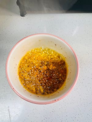 Versate abbondante olio in una padella e fatelo scaldare. Quando sentite un rumore sfrigolante, versatelo sul peperoncino in polvere e mescolate bene.