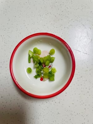 Lavare e tritare il coriandolo e i cipollotti.