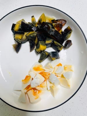 First, boil the salted eggs and preserved eggs until cooked, peel off the shells, and cut them into small cubes. Set aside.