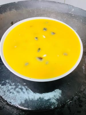 4. Cubra el recipiente con film transparente (o una tapa de vidrio) y perfore varios agujeros pequeños con un palillo. Una vez que el agua de la olla hierva, coloque el recipiente dentro. Si usa film transparente: cocine al vapor a fuego medio durante 8 minutos, luego apague el fuego y deje reposar 2 minutos. Si usa una tapa de vidrio: cocine al vapor durante 10 minutos, luego apague el fuego y deje reposar 1 minuto. Retire la tapa y agítela; la mezcla de huevo debe estar cuajada, pero sin grumos.