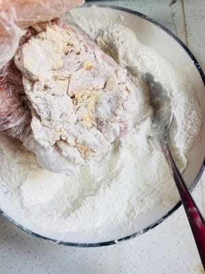 5. 衣をつけた鶏もも肉を小麦粉の衣に入れ、手で何度もこねてこすり合わせ、できるだけ小麦粉をまぶします。後で使うので、お皿に盛り付けます（面倒な方はキッチンペーパーの上に置いても構いません）。