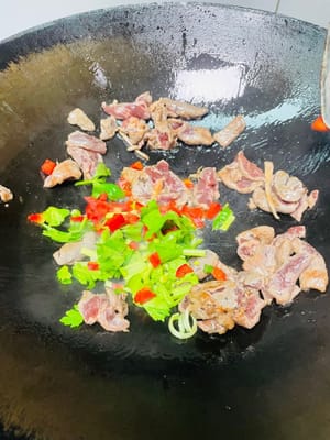Scaldare l'olio in un wok, aggiungere la carne marinata, soffriggere velocemente a fuoco vivo finché non cambia colore, quindi toglierla dal wok (non cuocerla troppo). Aggiungere il sedano e i peperoncini rossi e soffriggere brevemente finché non sono cotti.