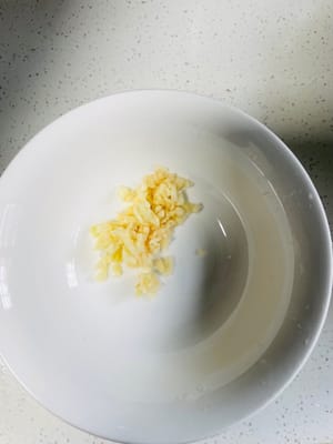 Per prima cosa, mettete in una ciotola l'aglio tritato, 1 cucchiaio di peperoncino in polvere e 1 cucchiaio di semi di sesamo bianco.