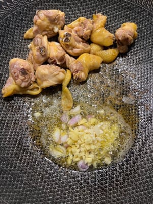Freír los muslos de pollo hasta que estén dorados. Agregue el ajo, las chalotas y el jengibre.