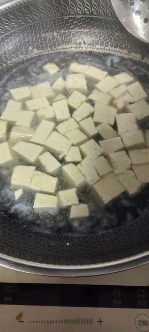 냄비에 물을 끓이고, 잘게 썬 두부를 넣은 후 소금 1티스푼을 넣고 2분간 삶습니다. 이렇게 하면 두부가 부서지는 것을 방지할 수 있습니다. 두부가 익으면 건져내고 물기를 빼줍니다.