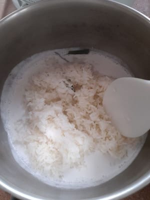 もち米を15分蒸した後、取り出して容器に入れ、先ほど茹でておいたココナッツミルクと混ぜ合わせ、よくかき混ぜながらさらに20分蒸します。置いてから蓋をします。