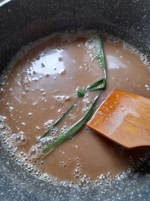 Vuelva a colocarlo en la olla, añada 250 ml de leche de coco instantánea, 1/4 de cucharadita de sal, 2 hojas de pandan y 1 cucharadita de azúcar granulada. Remueva, evitando que la leche de coco se separe.