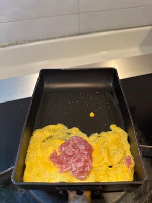 蛋液層稍微煮熟後，將一小塊豬肉碎放在中間