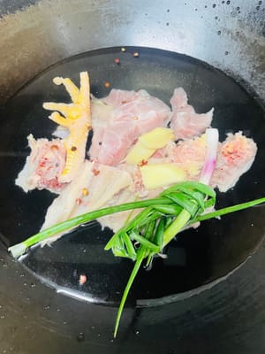 Lava la carcasa y la espina dorsal del pollo varias veces con agua limpia. Colócalas en una olla con agua fría, dos rodajas de jengibre y un poco de vino de cocina. Deja que hierva y escalda durante 5 minutos para eliminar la espuma de sangre. Retíralas y enjuágalas con agua tibia. Esto hará que la sopa quede clara y sin sabor a pescado.