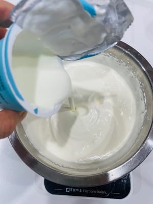 混合基础糊：往打发好的淡奶油里加酸奶，硅胶刮刀翻拌匀。再倒入晾凉到常温的吉利丁牛奶液，继续翻拌，让材料融合成顺滑慕斯糊。