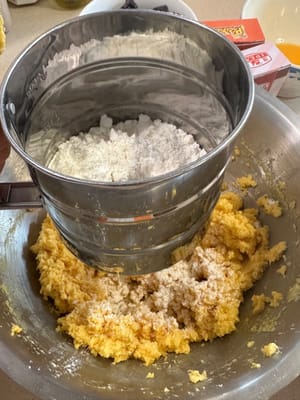 Luego, tamiza el recipiente con los ingredientes secos en la masa de mantequilla.