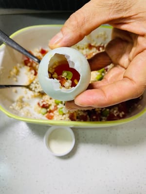 Con una cuchara pequeña, introduzca lentamente el relleno de arroz glutinoso en la cáscara de huevo salada y presione suavemente (sin ser demasiado brusco, ya que la cáscara se romperá). El relleno debe quedar bien apretado para que no se deshaga después de cocerse al vapor y tenga una textura más consistente.
