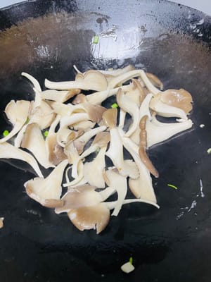 Tumis jamur tiram: Tambahkan sedikit minyak ke dalam wajan, masukkan bagian putih daun bawang yang sudah dicincang, lalu tumis dengan api sedang-kecil hingga harum. Kemudian, masukkan jamur tiram yang sudah ditiriskan dan tumis cepat dengan api besar.