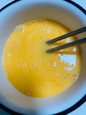 Persiapan telur: Ambil telur lainnya, pecahkan ke dalam mangkuk, dan aduk kuat-kuat menggunakan sumpit sampai putih dan kuning telur tercampur sempurna.