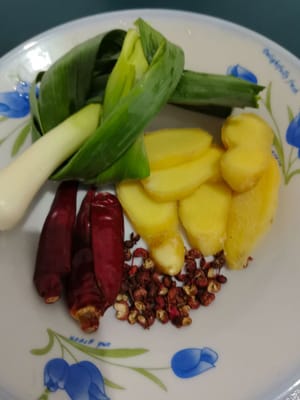 Satu batang daun bawang yang diikat simpul, enam atau tujuh iris jahe, tiga buah cabai kering, dan sekitar dua puluh butir merica.