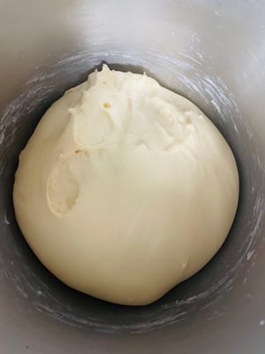 Sacar la masa que haya doblado su tamaño, desgasificarla, dividirla en trozos de 85 gramos, hacer bolitas y dejar reposar 15 minutos (tapar con film).