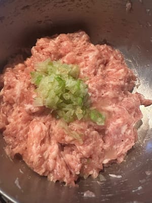 ในกระทะที่ใส่น้ำมันแล้ว ผัดต้นหอมซอยจนมีกลิ่นหอม แล้วใส่ลงไปในเนื้อสับ
