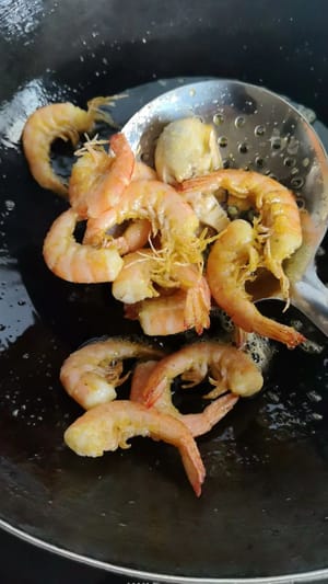 Heat oil in a wok to 60% of its maximum temperature. Add the prepared shrimp and fry over medium heat until the shells are crispy.