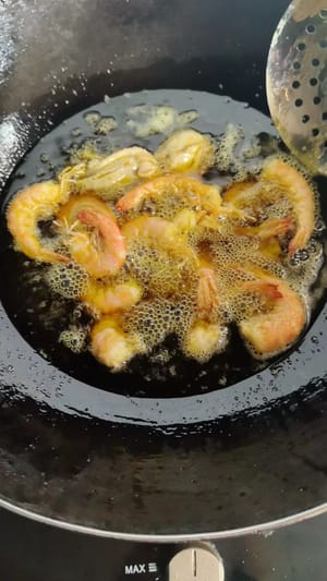 Heat oil in a wok to 60% of its maximum temperature. Add the prepared shrimp and fry over medium heat until the shells are crispy.