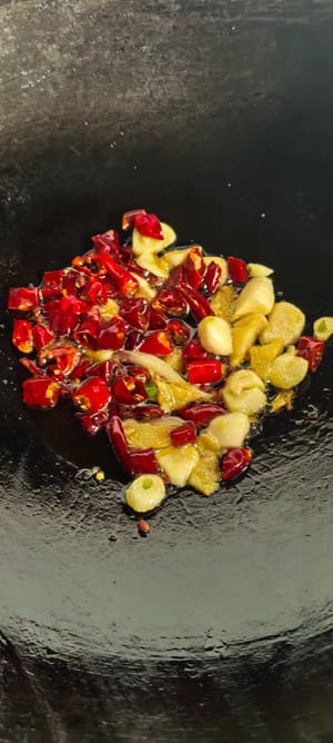 Pour out some of the excess oil. Heat the oil again, then sauté ginger, garlic, and dried chili peppers until fragrant. Add a spoonful of dry pot sauce, a teaspoon of light soy sauce, a little oyster sauce, and a pinch of salt.