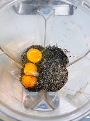 Coloque el ñame chino cortado en cubitos y los dátiles rojos en una licuadora, agregue 3 huevos, 75 g de cubos de pasta de sésamo negro y polvo de sésamo negro y luego vierta aproximadamente 50 g de agua.