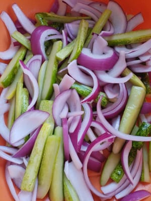 Versare le striscioline di cipolla e cetriolo in una pentola, aggiungere un cucchiaio di sale e lasciare marinare per 5 minuti.